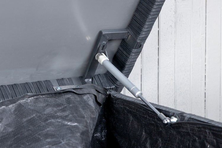 Szene mit einem gemusterten Teppich, einer Bank mit Hocker, einer Handtasche und Schuhen in einem hellen Raum.