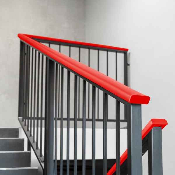 Treppengeländer aus Metall mit rotem Handlauf aus Kunststoff und dunklen vertikalen Stäben.