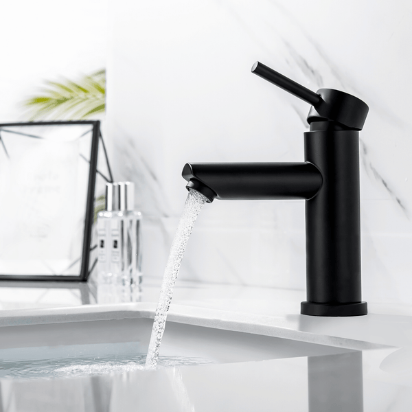 Moderne schwarze Einhebel Waschtischarmatur mit fließendem Wasser vor einer hellen Marmorwand im Badezimmer.