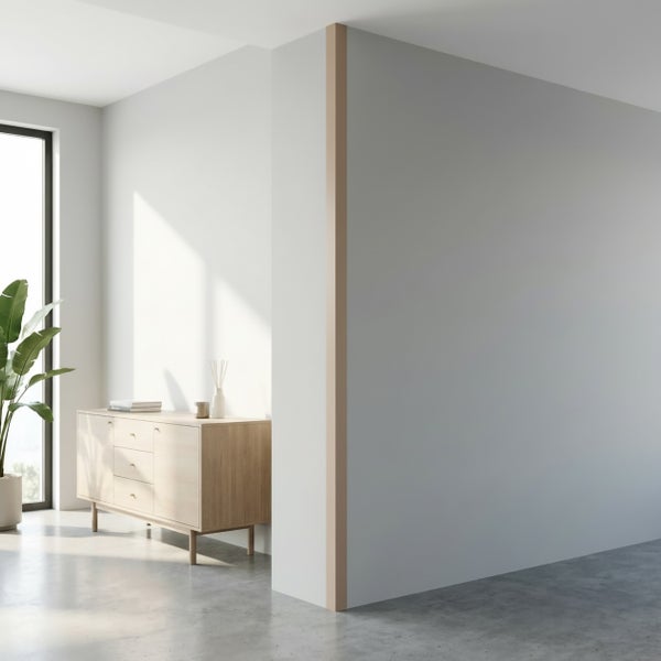 Heller Innenraum mit einer Holzanrichte vor einer Fensterfront und einer dekorativen Kante an der Wandecke auf einem Betonboden.