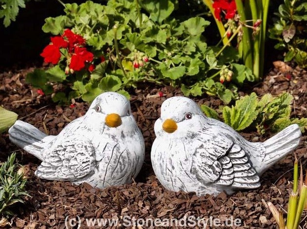 Zwei dekorative Gartenfiguren in Vogelform aus wetterfestem Steinguss im Blumenbeet
