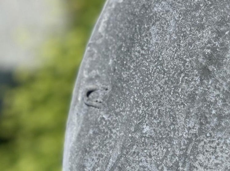 Detailaufnahme einer strukturierten Oberfläche aus Beton mit einer kleinen Einkerbung am Rand.