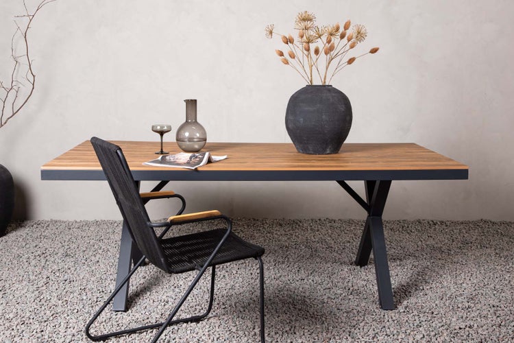 Gartenszene mit Esstisch, Stuhl, Gläsern und Dekoration auf Kiesboden.