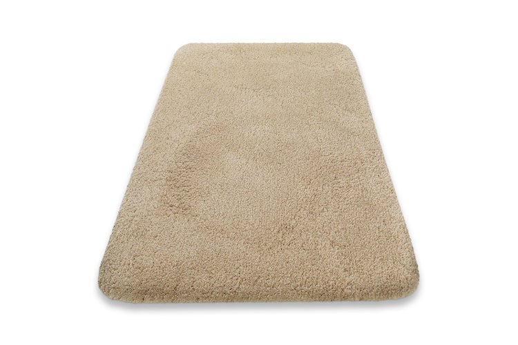 Rechteckige beige Badematte mit Hochflor und abgerundeten Ecken.