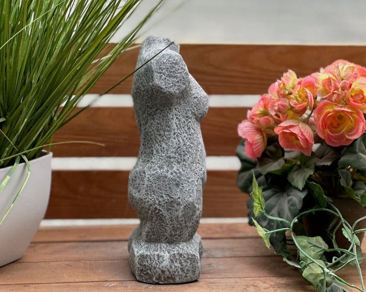 Dekofigur Frauentorso in Steinoptik auf einem Holztisch neben Blumen und Gras.