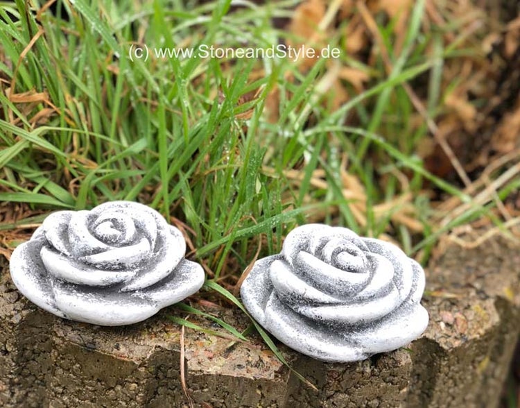 Zwei dekorative Rosenfiguren aus Stein zur Gartendekoration in einer Rasenlandschaft.