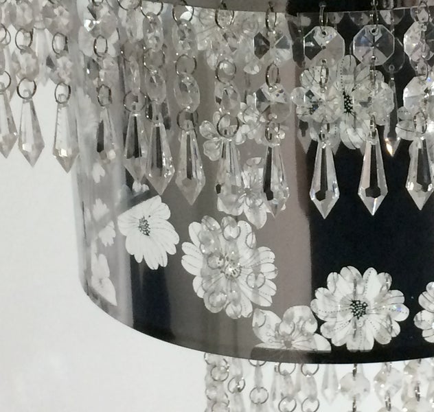 Detailaufnahme einer Lampe mit Blumendekor und Kristallanhängern