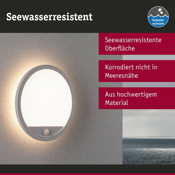 Runde LED Außenwandleuchte mit Bewegungsmelder an einer Hausfassade montiert, strahlt warmes Licht aus.