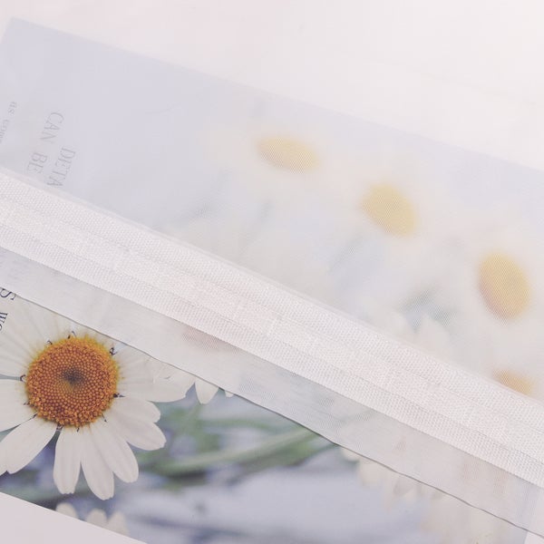 Transparente Dokumentenhülle mit Reißverschluss und Gänseblümchen-Motiv.