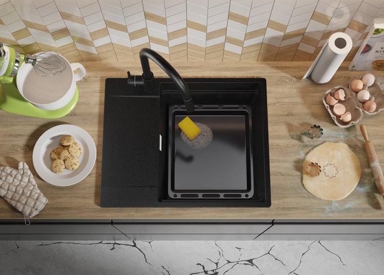 Küchenspüle aus schwarzem Material mit Spülmittel, Kochutensilien und Zutaten auf der Arbeitsfläche