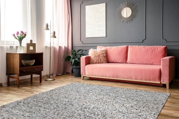 Helles Wohnzimmer mit grau gemustertem Teppich auf Holzboden, rosa Sofa und grauer Wand mit Zierleisten.