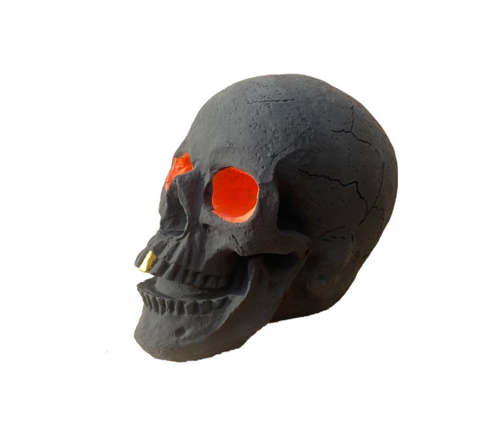 Dekorativer Totenkopf mit leuchtenden Augen und goldenem Nasenschmuck als Halloween Tischdekoration