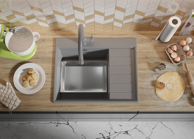 Küchenszene mit Spüle, Armatur, Rührgerät, Keksen, Eiern und Teig auf einer Arbeitsplatte.