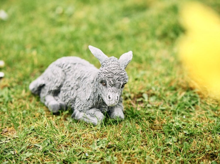 Dekorative Gartenfigur Esel aus Stein für den Außenbereich im Gras liegend.