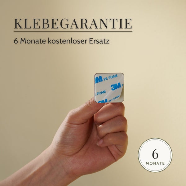 Hand hält einen quadratischen Klebepad mit Klebegarantie und sechs Monaten kostenlosem Ersatz.