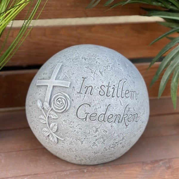 Grabkugel aus Stein mit Inschrift In stillem Gedenken, Kreuz und Rosenmotiv als Grabschmuck.