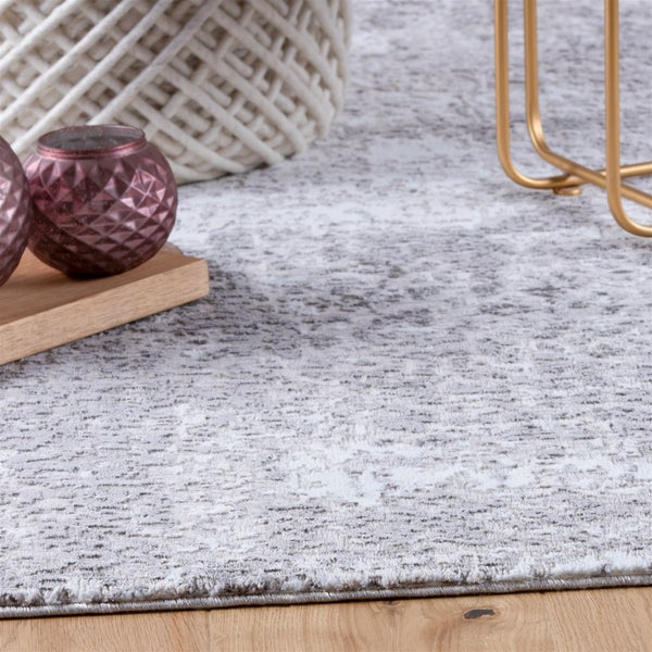 Gemusterter Teppich in Grau und Weiß auf Holzboden mit Wohnzimmereinrichtung wie Tischbeinen und Dekovasen.