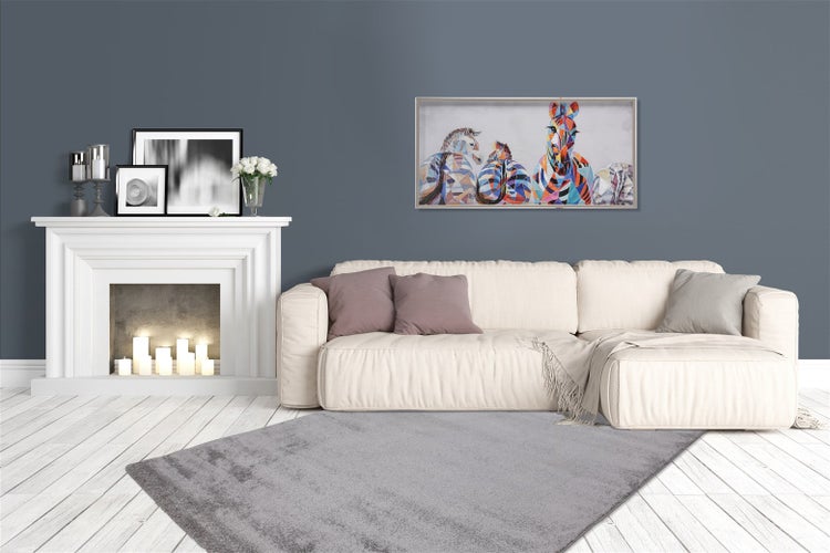 Modernes, helles Wohnzimmer mit modularem Sofa, grauem Teppich auf Holzboden, weißem Dekokamin mit Kerzen und einem bunten Zebrakunstwerk an der Wand.