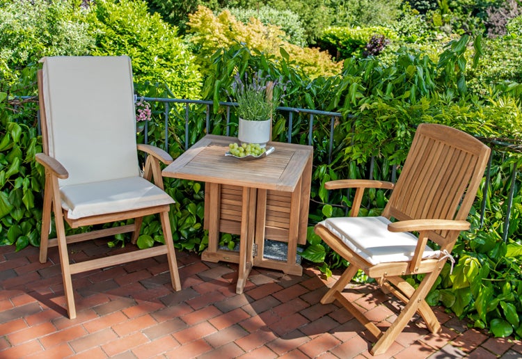 Gartenszene mit Teakholzmöbeln bestehend aus zwei Stühlen und einem Klapptisch