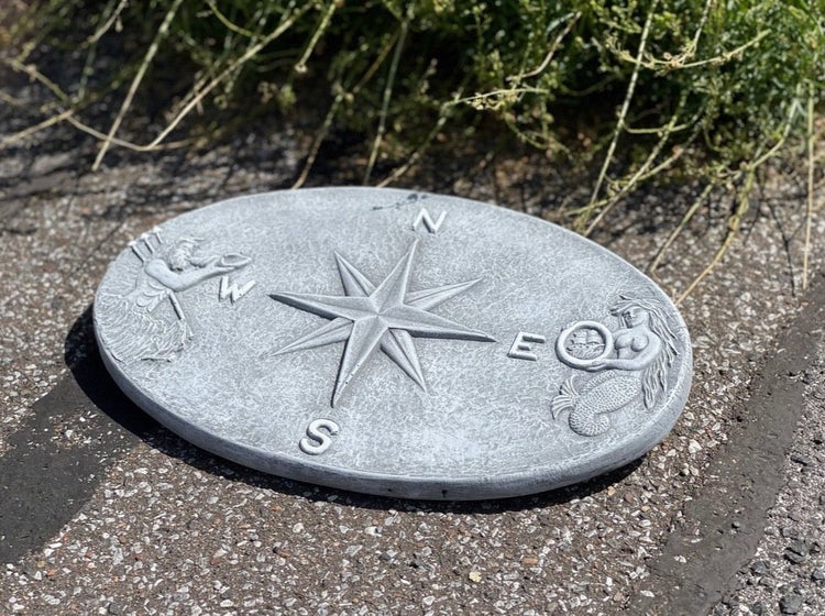 Runde Gartenplatte aus Beton mit eingeprägtem Kompass Motiv und maritimen Figuren als Dekorationselement für den Außenbereich