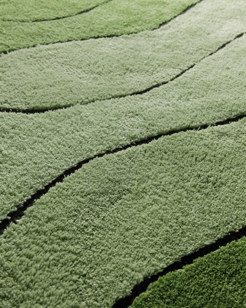 Grüner Hochflor-Teppich mit geschwungenen Linien und weicher Textur.