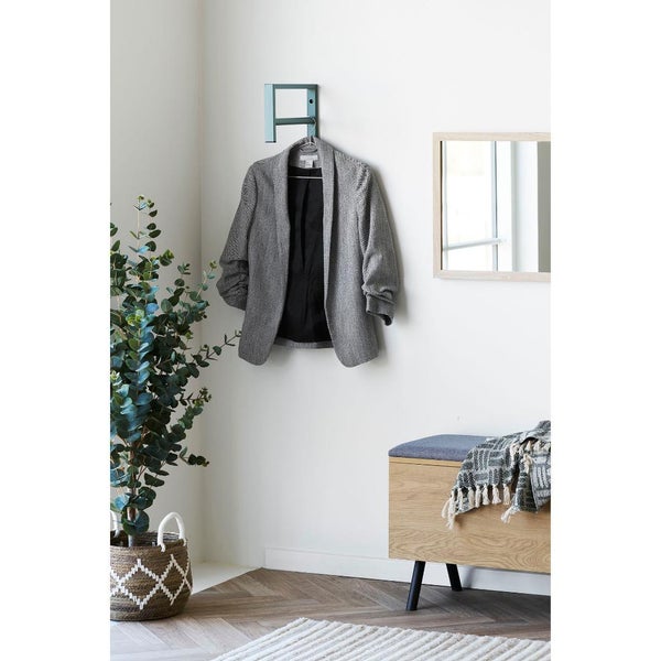 Helle Inneneinrichtung mit Wandgarderobe, Spiegel, Bank und Zimmerpflanze im Korb.