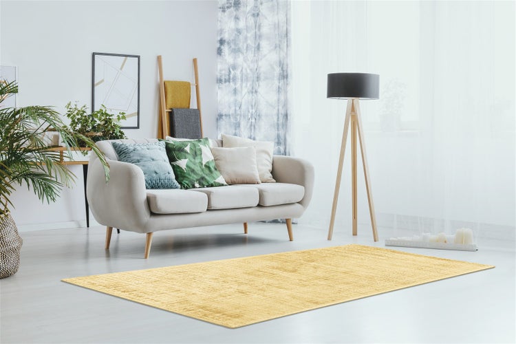 Heller, geräumiger Wohnbereich mit modernem Sofa, Stehlampe aus Holz und einem rechteckigen gelben Teppich auf hellem Boden.