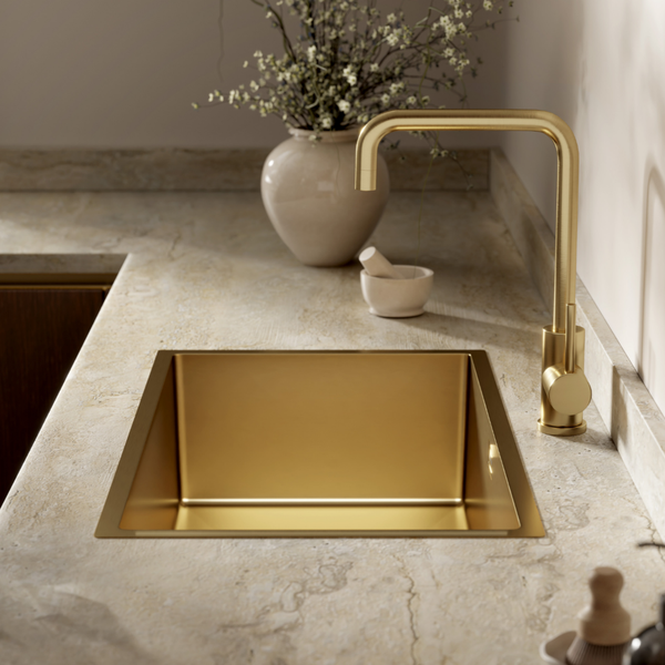 Goldfarbenes Einbauspüle mit passender Küchenarmatur in einer modernen Küche mit einer Arbeitsplatte aus Naturstein.