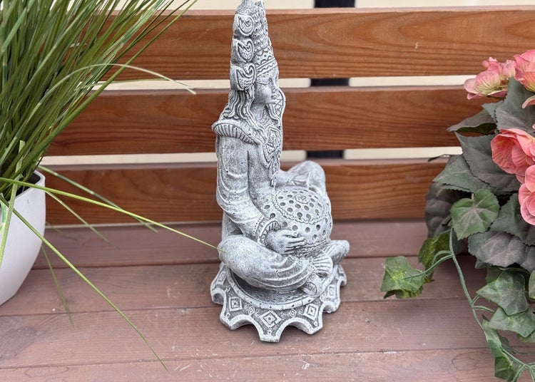 Gartenfigur einer sitzenden Göttin im Steinguss-Design, die eine gemusterte Kugel hält, platziert auf Holzbrettern.