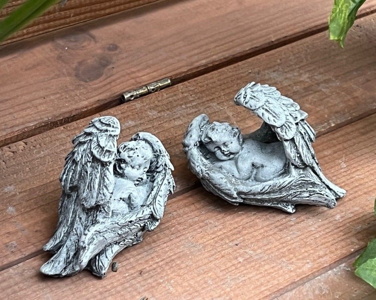 Zwei kleine Engel Figuren aus Stein als Dekoration für den Garten oder Innenbereich.