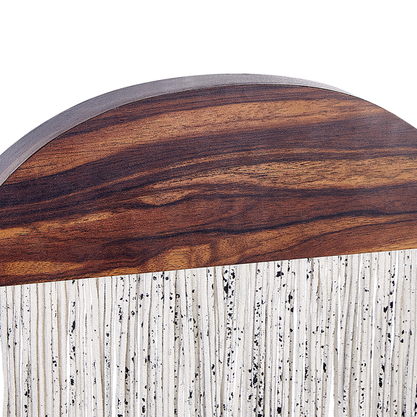 Detailansicht einer Wanddekoration mit halbrundem Holzelement in dunkler Maserung und hängenden, gesprenkelten weißen Kordeln.