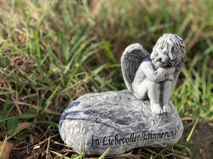 Grabschmuck in Form eines Engels auf einem Stein mit der Aufschrift In liebevoller Erinnerung als Dekoration für den Garten
