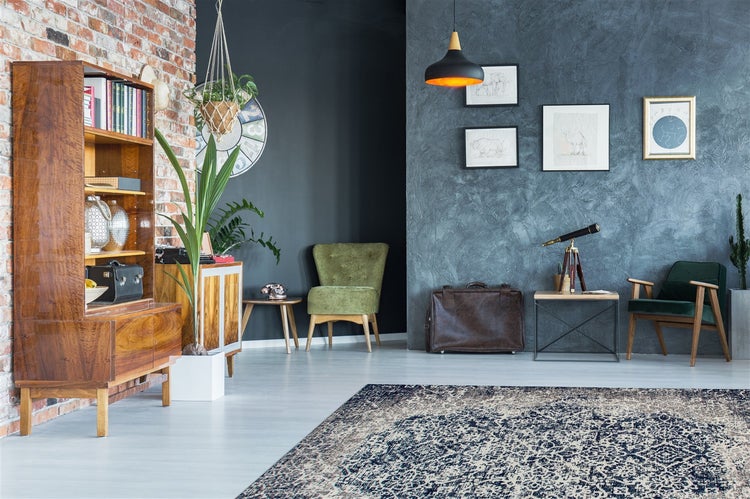 Wohnzimmer im Vintage-Stil mit Ziegelwand, blauer Wand, Holzmöbeln, Sesseln und einem großen gemusterten Teppich in Blau und Beige.