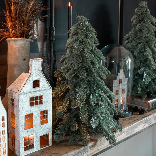 Dekorative Szene mit künstlichen Weihnachtsbäumen, dekorativen Hauslaternen und saisonalen Akzenten.