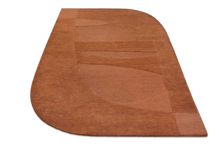 Terrakottafarbener Teppich mit asymmetrischer Form und geometrischem Muster.