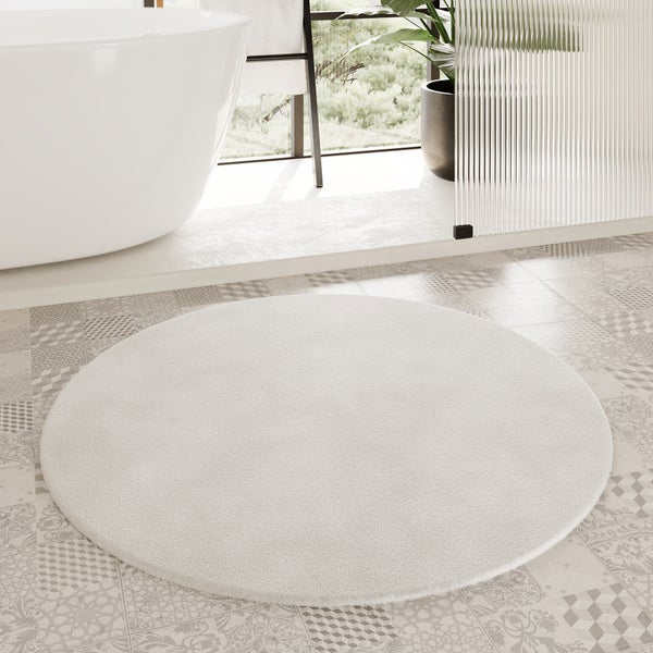 Runder, cremefarbener Hochflor-Teppich mit weicher Textur.