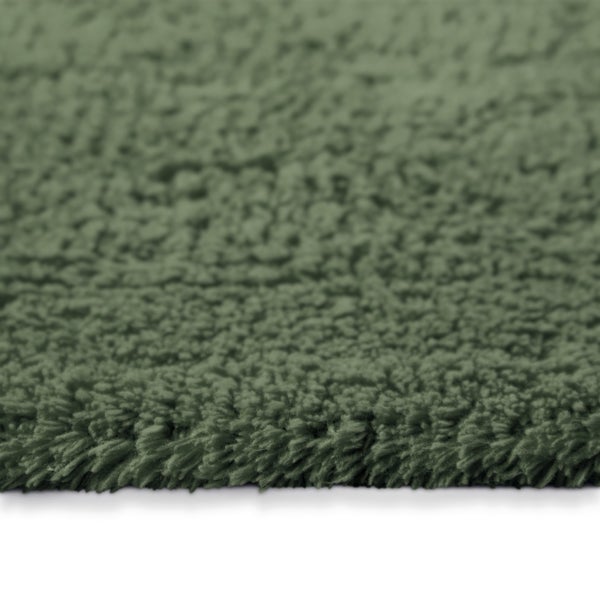 Nahaufnahme eines grünen Hochflor-Badeteppichs mit weicher, zotteliger Textur.