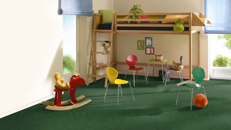 Helles Kinderzimmer mit Hochbett aus Holz, grünem Teppichboden, bunten Stühlen und einem Schaukelpferd.