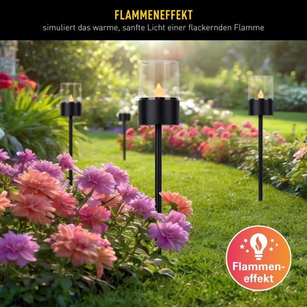 Gartenszene mit mehreren Solarleuchten mit Flammeneffekt zwischen Blumenbeeten