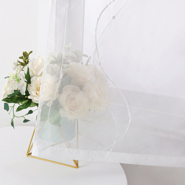 Dekoschals mit floralem Muster auf einem Tisch mit Blumenarrangement