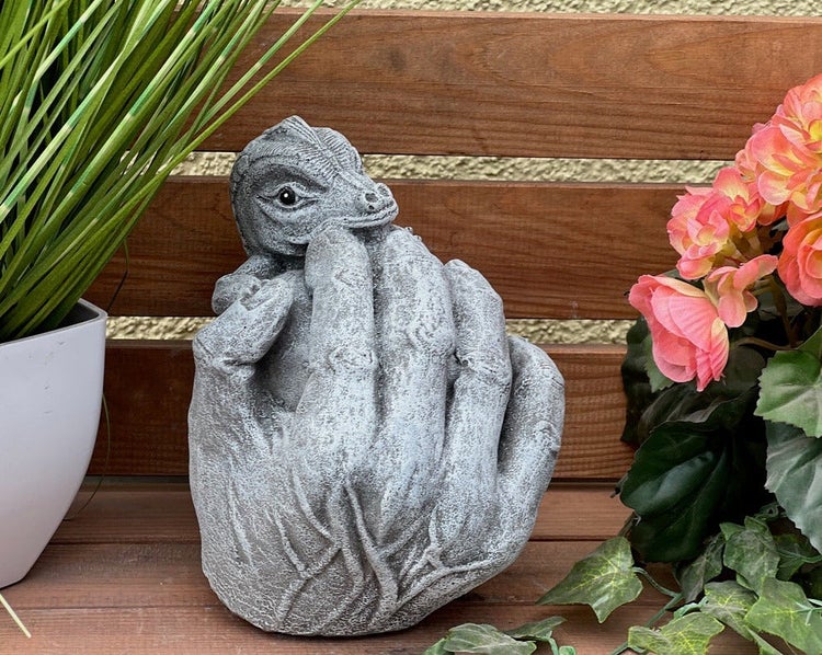 Gartenfigur aus Steinguss in Form einer Hand, die einen kleinen Drachen hält.