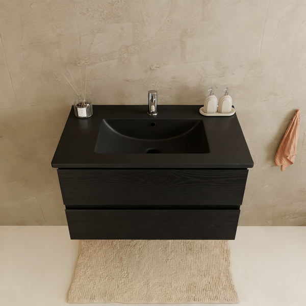 Moderner Waschtisch mit zwei Auszügen und integriertem Becken vor einer strukturierten Wand mit Accessoires.