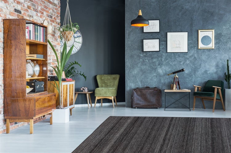 Hell eingerichtetes Wohnzimmer mit einer Backsteinwand, einem Holzregal, blauer Strukturwand und einem dunkelgrauen Teppich.