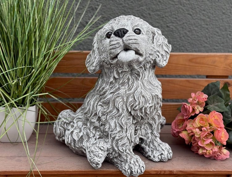 Dekorative Hundefigur aus Steinguss für den Garten, sitzender Hund mit lockigem Fell auf einer Holzbank.