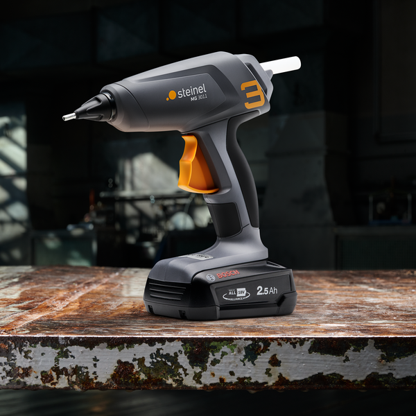 Akku-Heißklebepistole Steinel MG 3011 mit 18 Volt Bosch Akku auf einem Arbeitstisch.