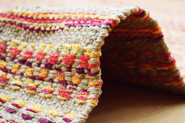 Rechteckiger Webteppich mit buntem Streifenmuster und strukturierter Oberfläche.