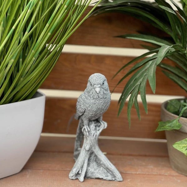 Dekorative Wellensittich Gartenfigur aus Stein für den Außenbereich auf einem Baumstamm stehend.