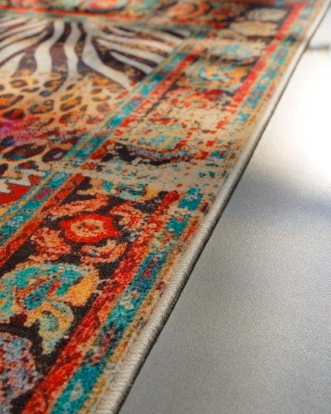 Nahaufnahme eines Teppichs mit Patchwork-Design aus Tiermustern und Ornamenten sowie einer Kettelung am Rand.