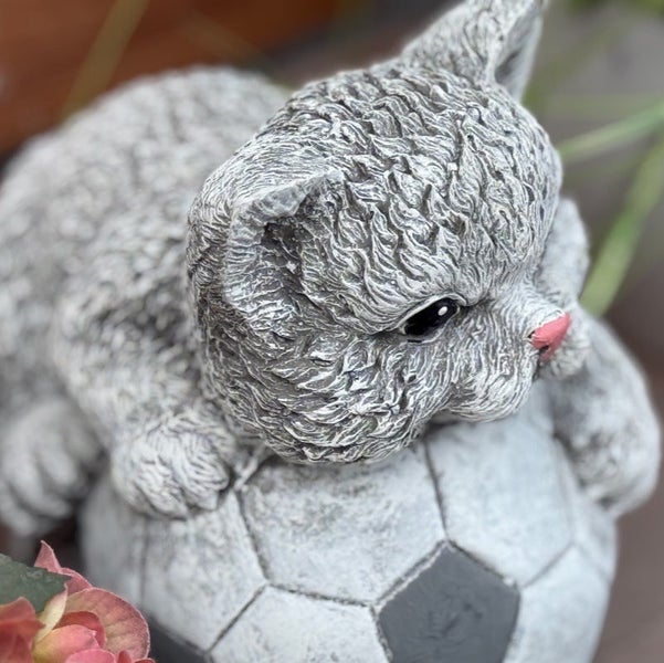 Dekorative Gartenfigur Katze auf einem Fußball, aus wetterfestem Kunststein für den Außenbereich.
