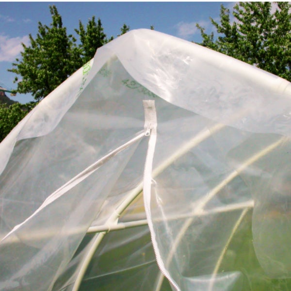Detailansicht eines Gewächshauses mit Folienabdeckung und Reißverschlussöffnung.